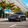 A 2024 Audi Q8 Sportback 55 e-tron quattro midsize SUV model driving past a line of palm trees outside a stadium