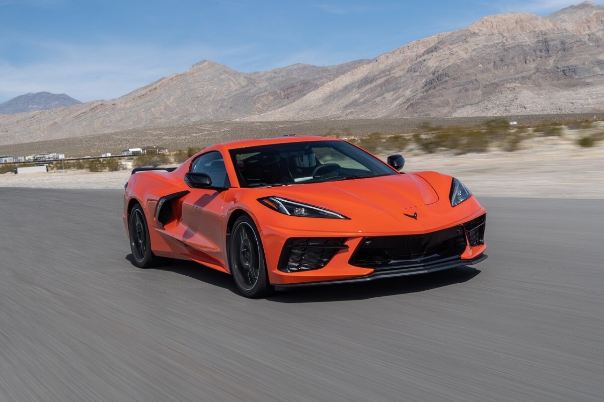 An orange C8 Chevrolet Corvette Stingray drives on a desert track.