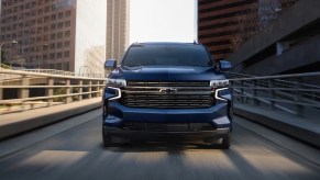 A blue 2023 Chevrolet Tahoe full-size SUV is driving on the road.