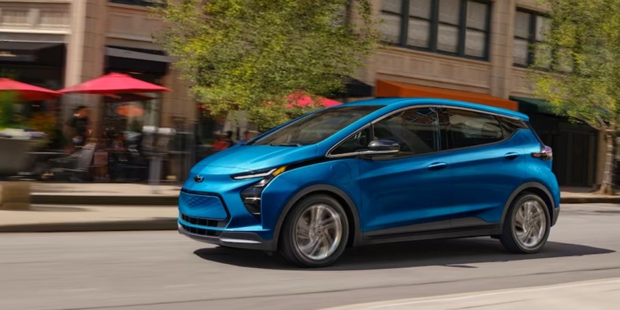 A blue 2023 Chevy Bolt EV is driving on the road.