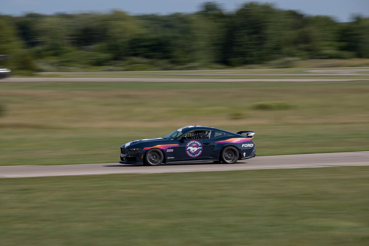 A Ford Mustang Dark Horse R shows off its new livery in a side profile shot on a track.