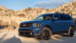 The side of a blue 2024 Kia Telluride that is parked off-road.