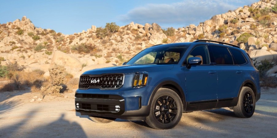 The side of a blue 2024 Kia Telluride that is parked off-road.