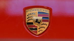 The Porsche logo featured on a red 911 Carrera 4 992 model at a Galeria Krakowska shopping mall exhibition