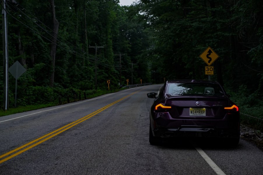 A BMW M240i parked in front of a curvy road sign