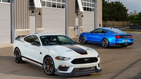 A manual set of Ford Mustang Mach 1s park next to a track.