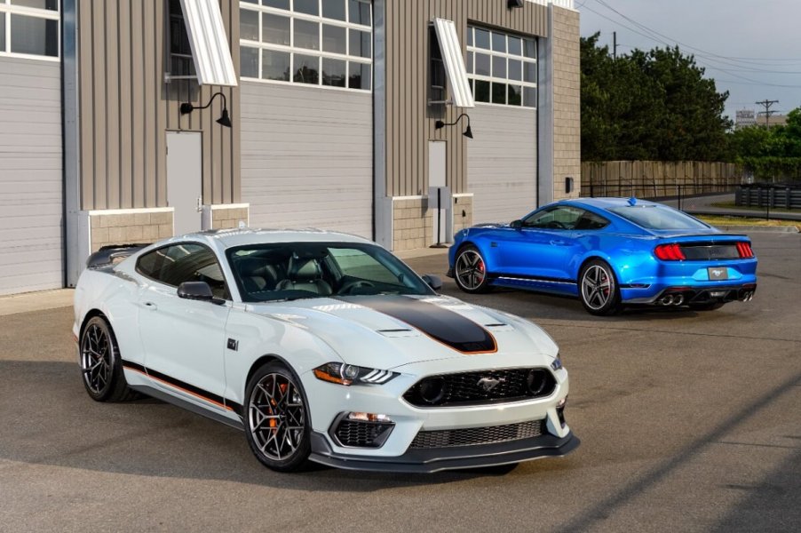 A manual set of Ford Mustang Mach 1s park next to a track.