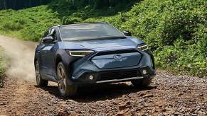 A blue Subaru Solterra small electric SUV is driving off-road.