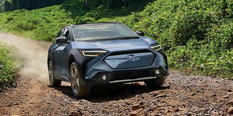 A blue Subaru Solterra small electric SUV is driving off-road.