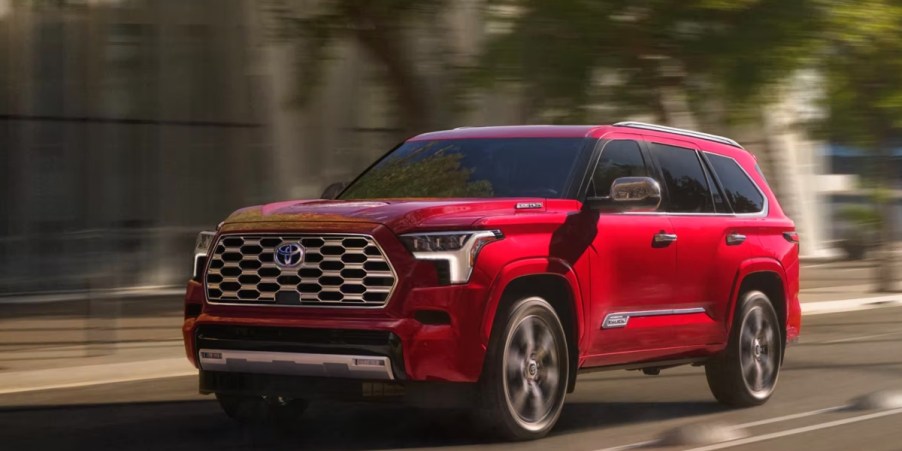 A red 2023 Toyota Sequoia full-size SUV is driving on the road.