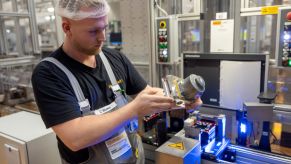 An employee checking a MK C2 braking system integrating the master cylinder, brake booster, and control systems