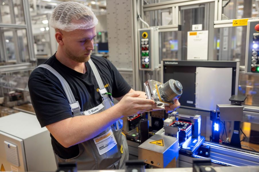 An employee checking a MK C2 braking system integrating the master cylinder, brake booster, and control systems