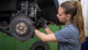 A mechanic changing the brake disc on a Land Rover Range Rover Evoque model in a workshop garage