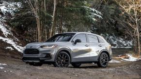 A 2024 Honda HR-V Sport subcompact SUV model parked on a muddy, worn, and snowy forest road