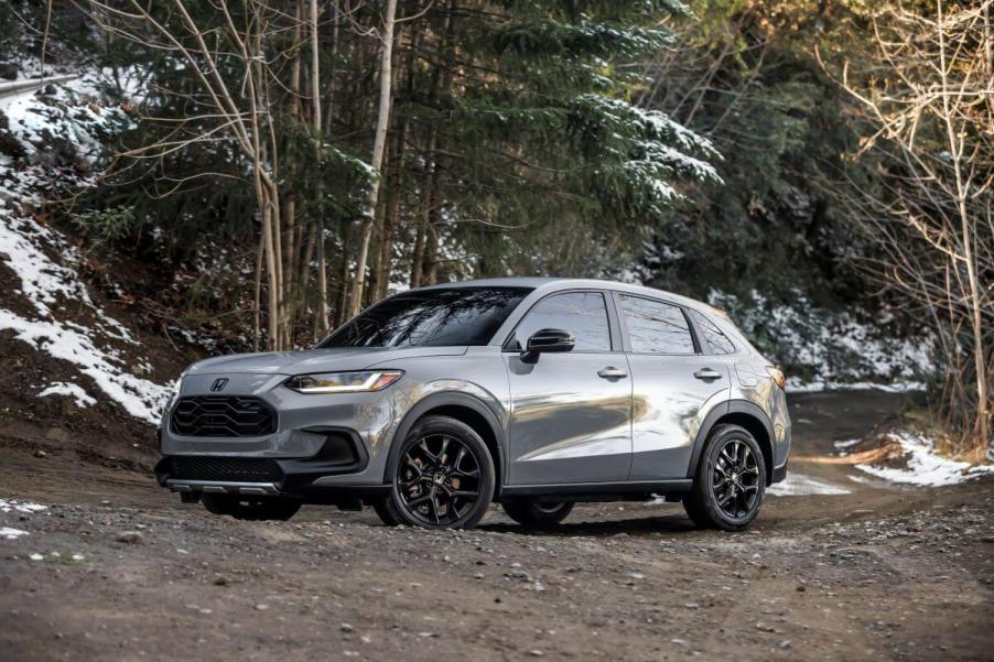 A 2024 Honda HR-V Sport subcompact SUV model parked on a muddy, worn, and snowy forest road