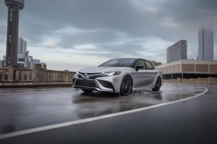 A 2024 Toyota Camry XSE AWD midsize sedan model driving on a wet road filled with puddles