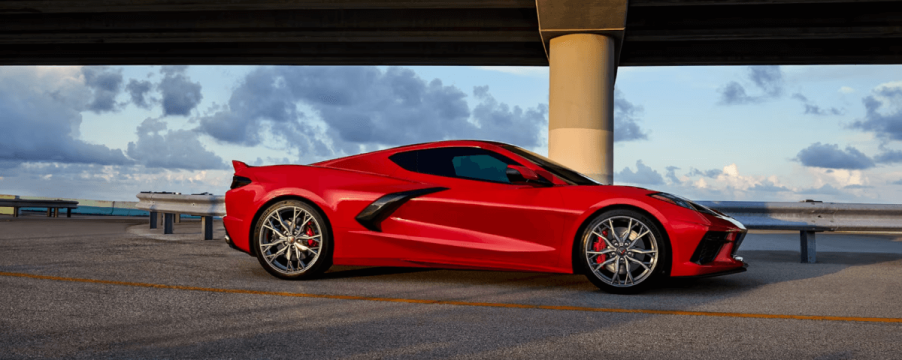 A 2024 Chevy Corvette Stingray performance sports car coupe model in Torch Red parked under a highway bridge