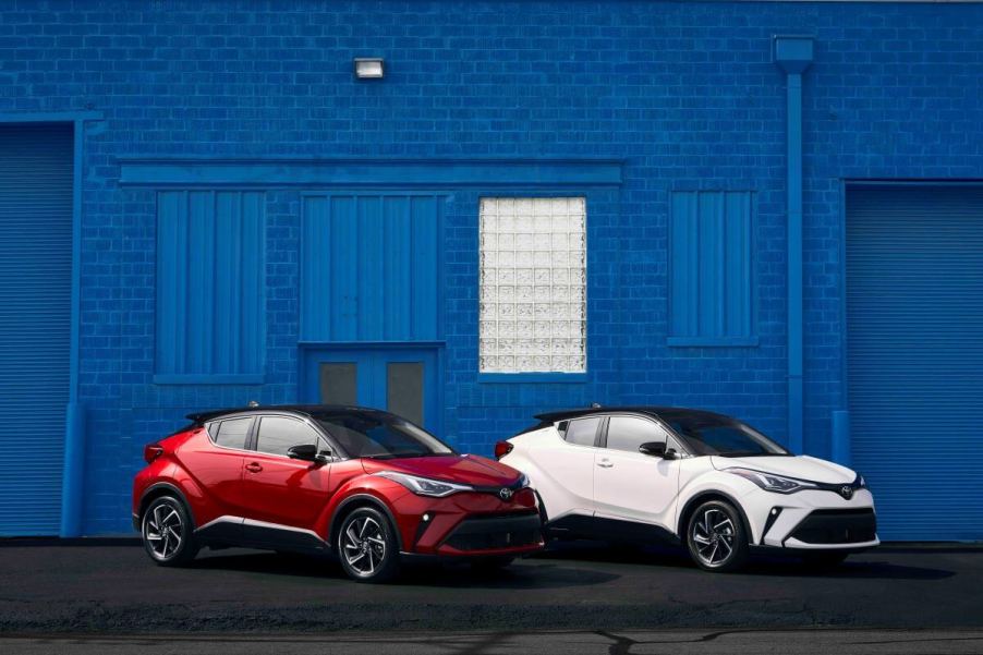 Red and white 2022 Toyota C-HR subcompact crossover SUV models parked in front of a blue painted brick wall