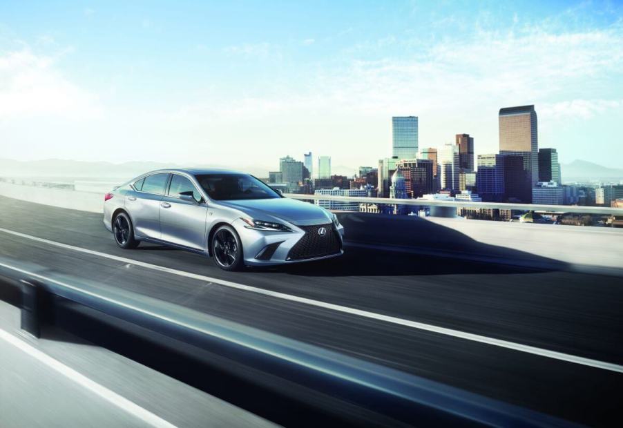 A 2024 Lexus ES midsize executive car/luxury sedan model driving on a highway overpass framed by a city skyline