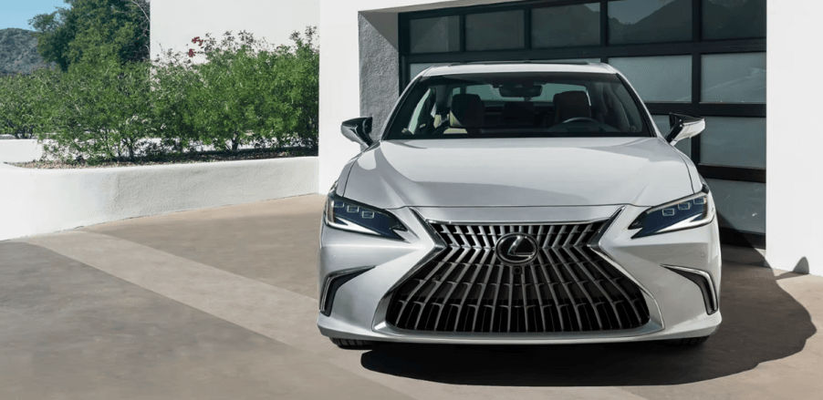 A 2024 Lexus ES Hybrid midsize executive car/luxury sedan model parked outside of a garage door