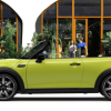 A banner of a side profile 2024 Mini Convertible model parked in front of a café restaurant patio