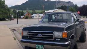 An old black Ford F-150 pickup truck parked in front of a mountain in Sundance, Wyoming.