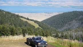 1988 Ford F-150 classic old truck parked on a mountainside in Montana, a lake visible in the background.