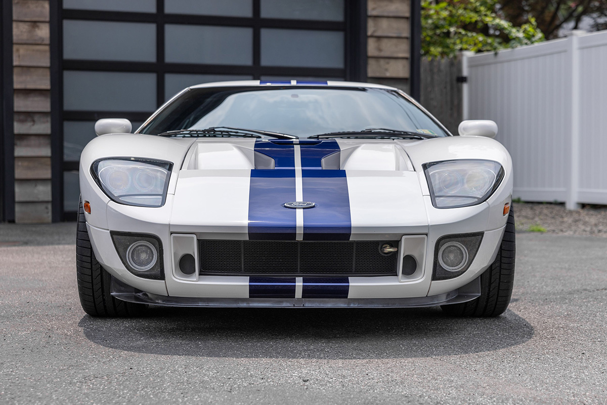 Front end of once abandoned 2005 Ford GT in white with blue racing stripes. 