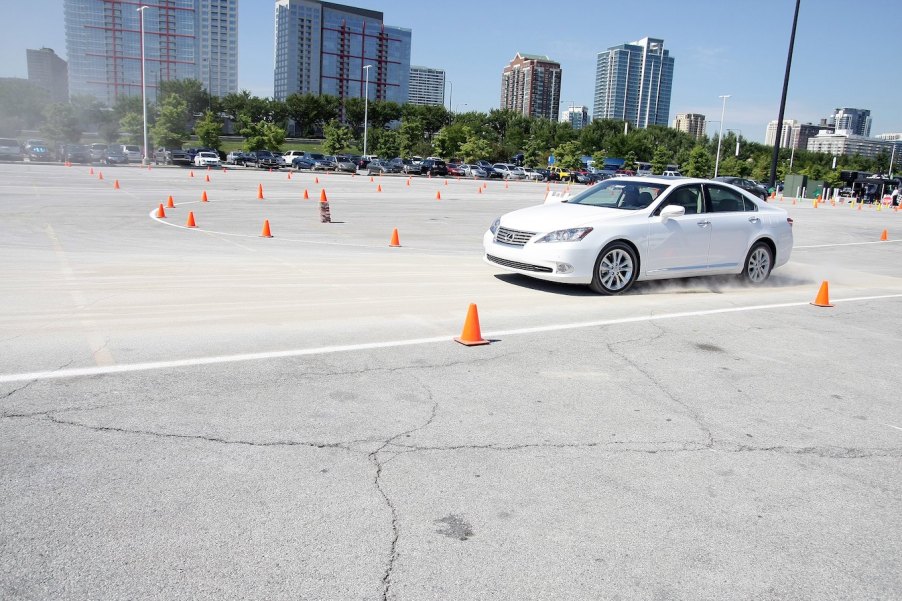 A white 2010 Lexus ES, one of the best used midsize luxury cars, in a parking lot with cones.