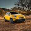 Bright yellow Fiat crossover parked off-road.