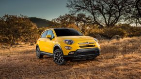 Bright yellow Fiat crossover parked off-road.