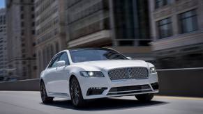 A CD-4 Lincoln Continental drives on an urban roadway with its lights on.