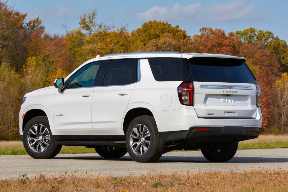 A white Chevrolet Tahoe SUV with a Duramax diesel, parked in front of a treeline.