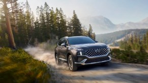 A gray 2023 Hyundai Santa Fe Hybrid midsize hybrid SUV is driving off-road.