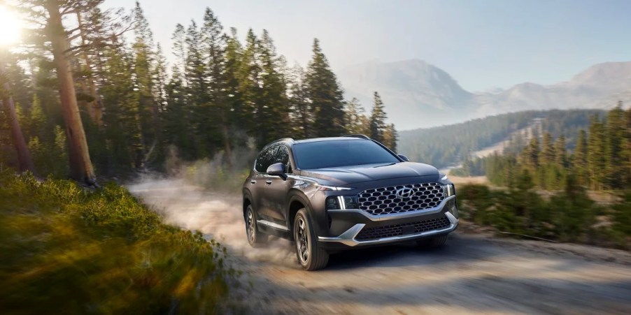 A gray 2023 Hyundai Santa Fe Hybrid midsize hybrid SUV is driving off-road.