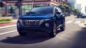 A blue 2023 Hyundai Tucson Hybrid small hybrid SUV is driving on the road.