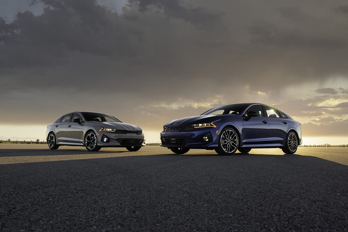 A set of 2023 Kia K5 midsize cars park under overcast skies.