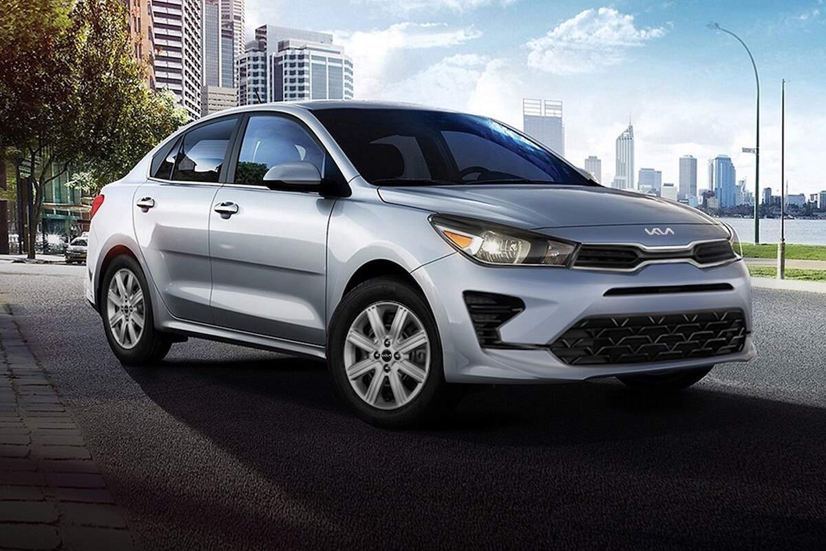 A silver 2023 Kia Rio parked in front of a city skyline