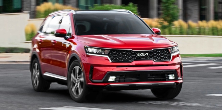 A red 2023 Kia Sorento hybrid midsize hybrid SUV is in the street. 