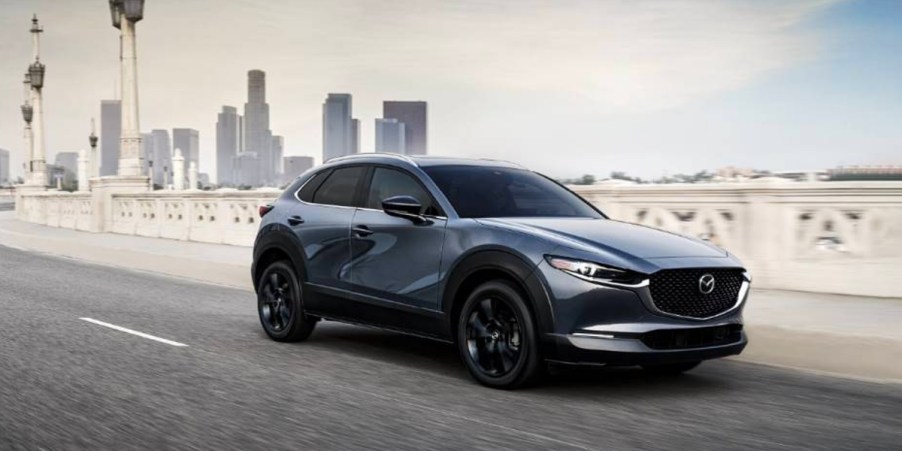 A blue 2023 Mazda CX-30 subcompact SUV is driving on the road.