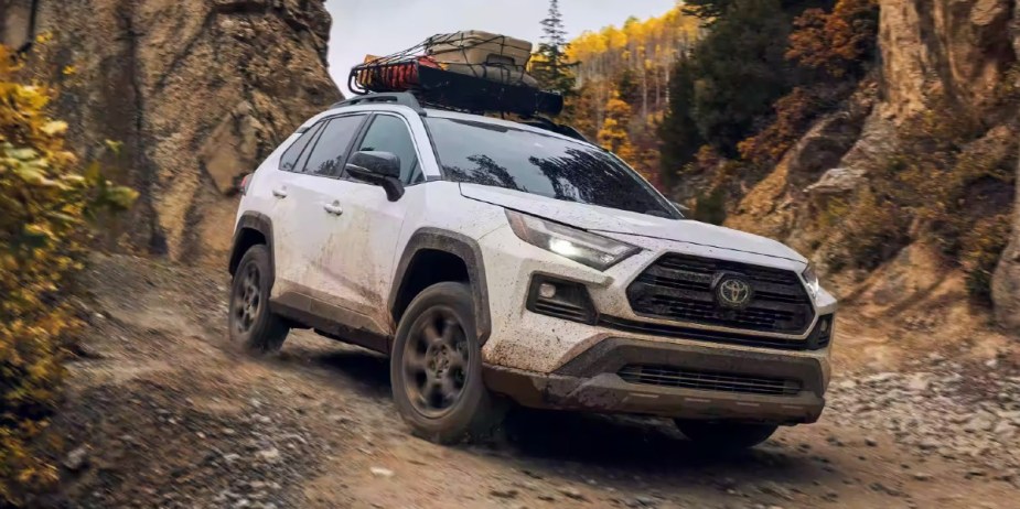 A white 2023 Toyota RAV4 small SUV is driving off-road. 