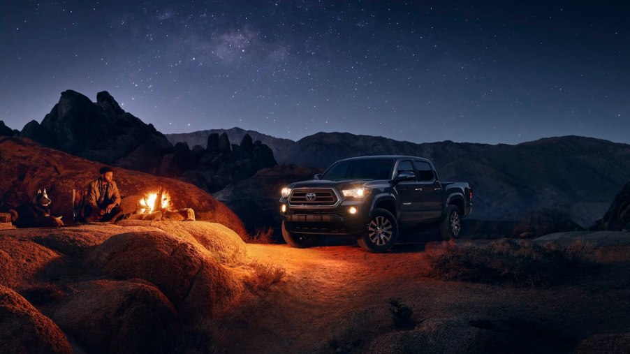 A 2023 Toyota Tacoma SR5 trim parked off-road, a campfire visible in the foreground.