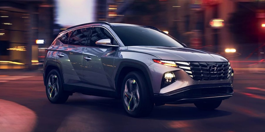 A gray 2024 Hyundai Tucson small SUV is driving on the road.