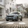 A 2024 Kia Seltos subcompact SUV model in Pluton Blue stopped at a cobblestone crosswalk