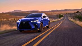 A 2024 Lexus NX 450h compact luxury SUV model driving down a desert highway road