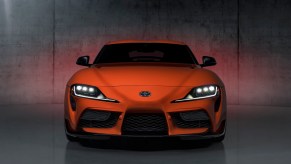 An orange Anniversary Edition 2024 Toyota GR Supra Mk5 parks in a studio.