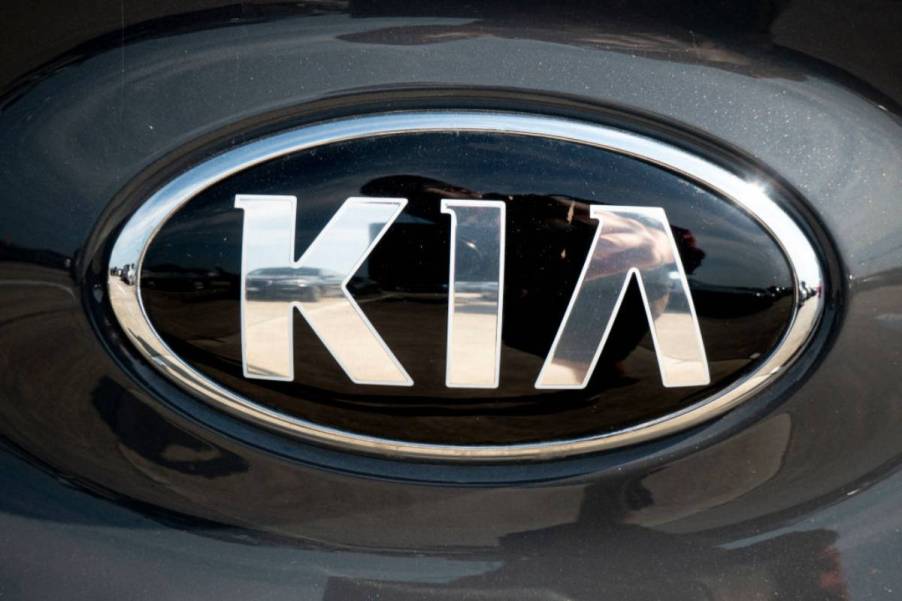 A silver Kia logo on the front of a car.