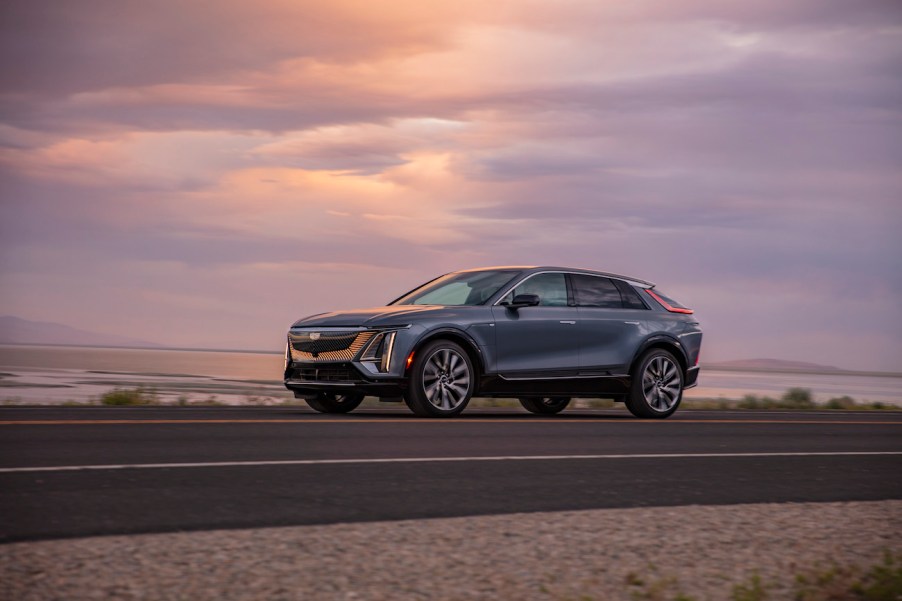 Driver side of the 2023 Cadillac LYRIQ in silver driving at dusk. The Lyriq is the premier Cadillac EV