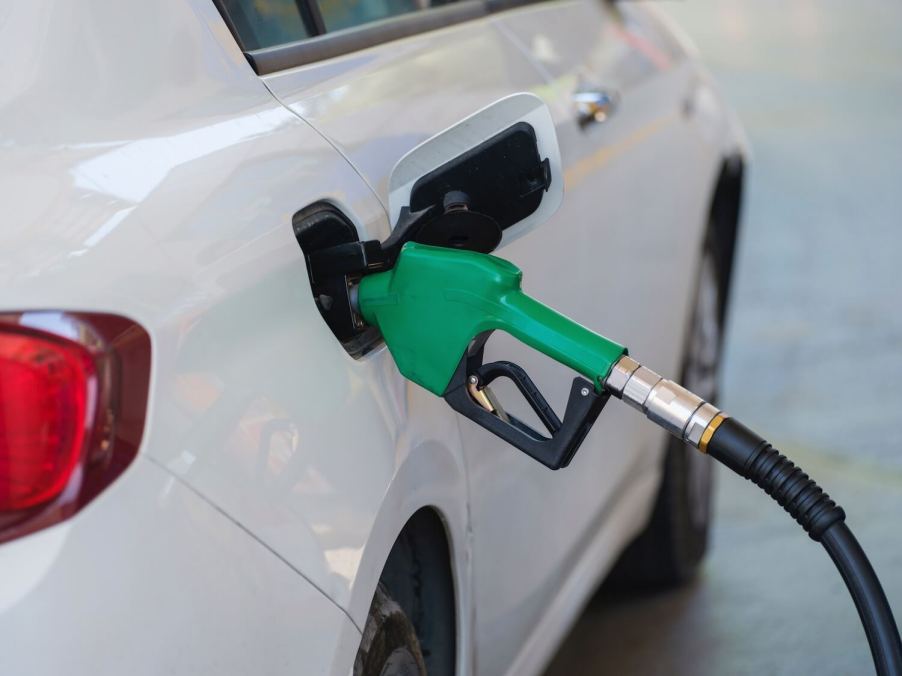 A green diesel fuel pump handle in the tank of a diesel crossover SUV.