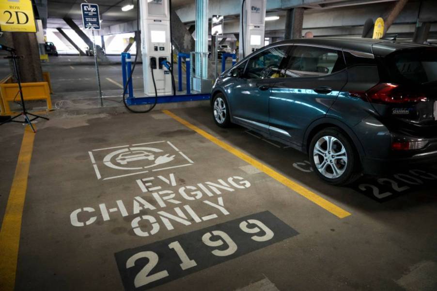 An electric car plugged in at a public charging station.